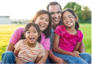 Smiling family sitting outside together